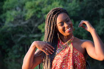 Black woman smiling and wearing a protective hairstyle with blonde and brown hair