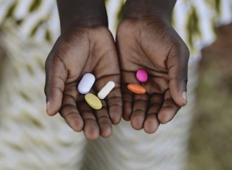 Hands holding different color vitamins.