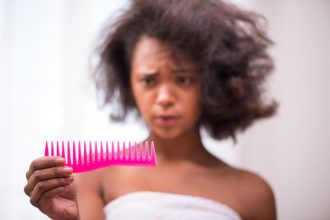 Black woman looking at hair in a comb